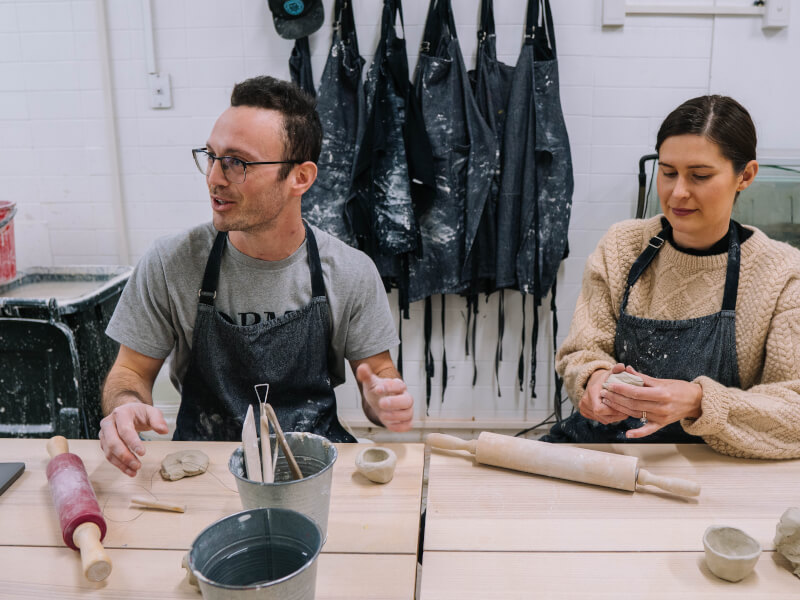 A couple work with clay in a hand building pottery class.